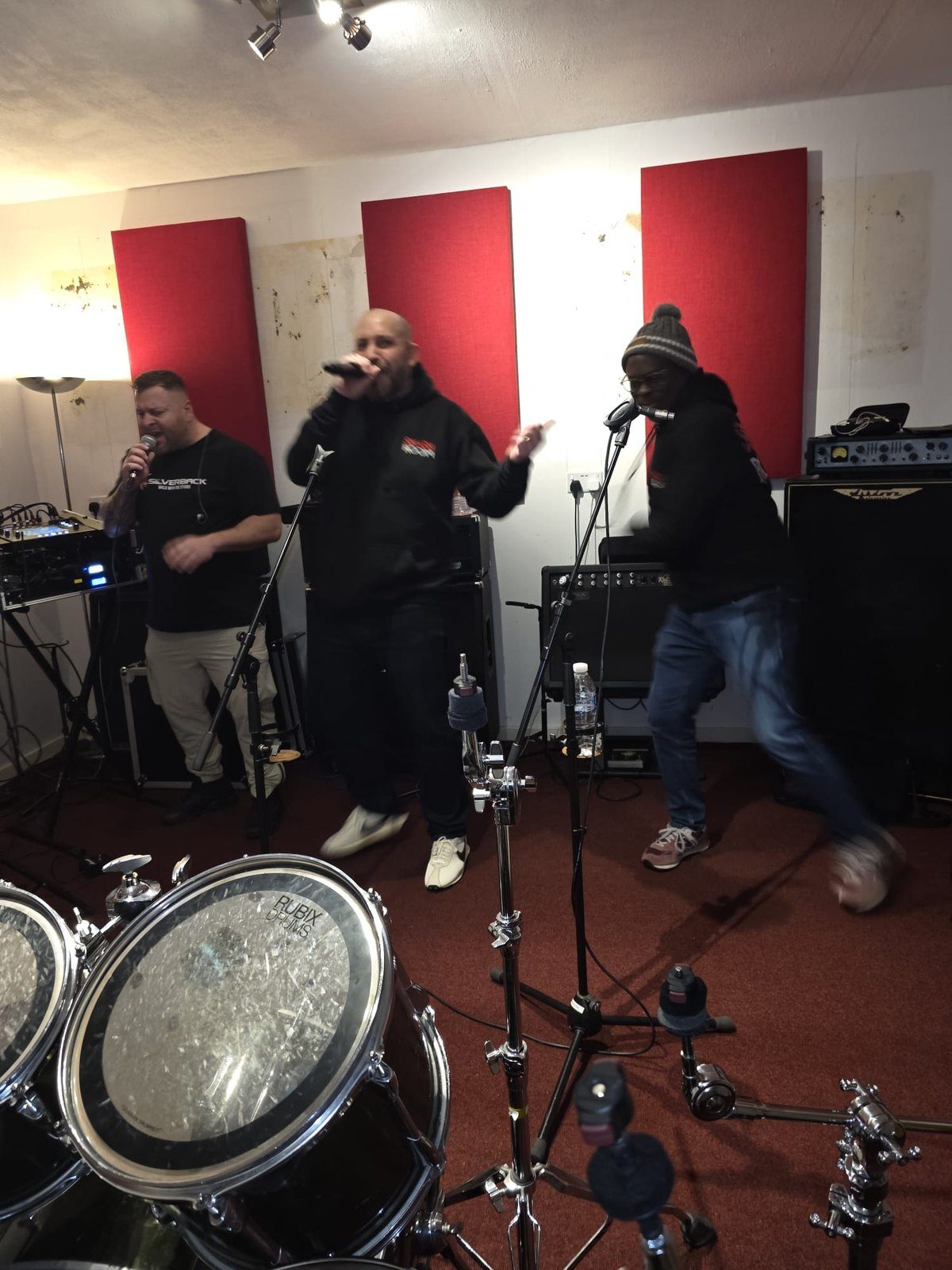 Two Smashroom members performing together at microphones, a drum kit in the foreground